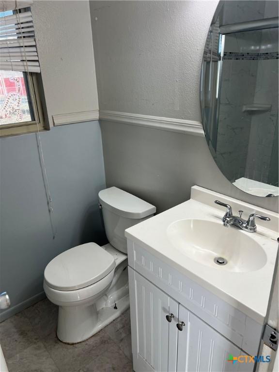 bathroom featuring vanity, toilet, and a shower with door