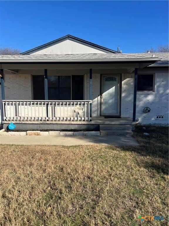 back of house featuring covered porch and a lawn