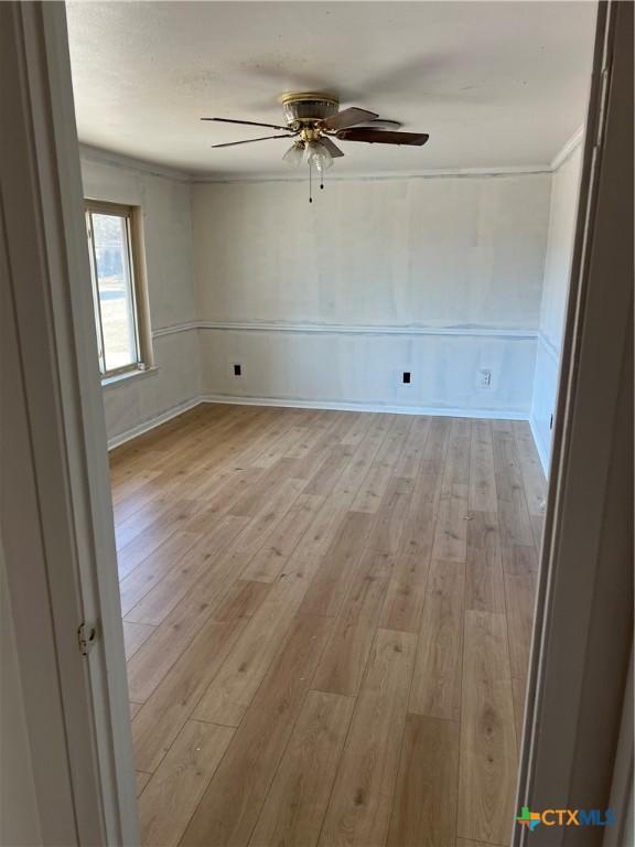 empty room with ceiling fan, ornamental molding, and light hardwood / wood-style flooring