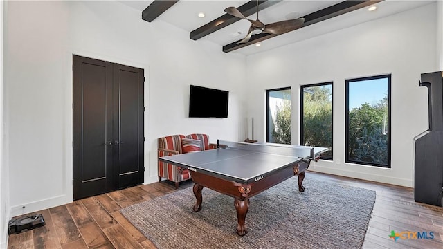 playroom with dark hardwood / wood-style flooring, beam ceiling, and a towering ceiling