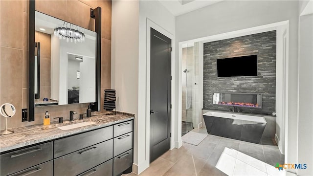 bathroom featuring a multi sided fireplace, vanity, plus walk in shower, and tile patterned flooring