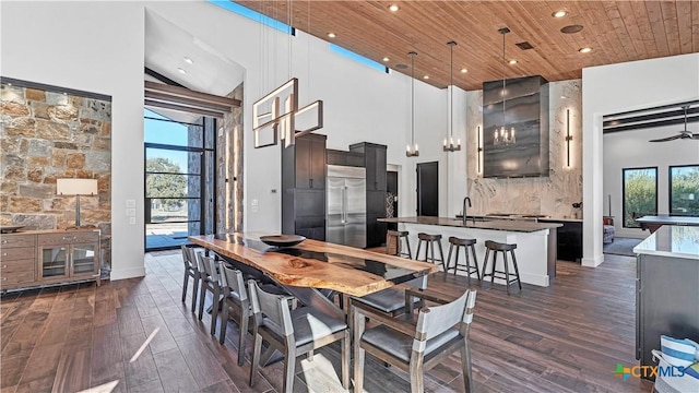 dining space featuring a high ceiling, ceiling fan, wooden ceiling, and dark hardwood / wood-style flooring