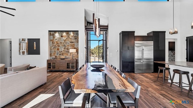 dining area with a high ceiling, dark hardwood / wood-style floors, and a chandelier