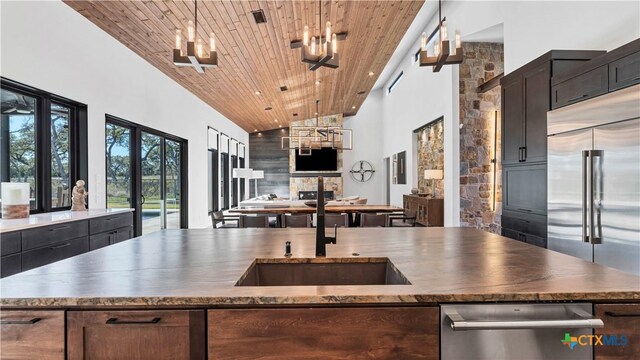 kitchen featuring sink, high vaulted ceiling, stainless steel appliances, decorative light fixtures, and wooden ceiling