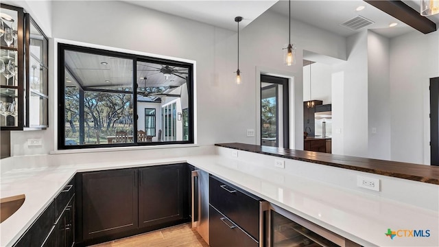 kitchen with wine cooler, hanging light fixtures, and light hardwood / wood-style floors