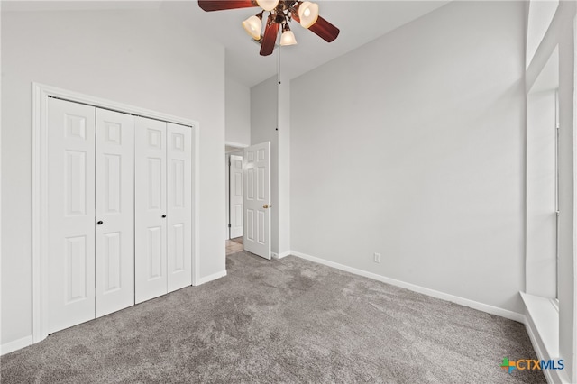 unfurnished bedroom with a high ceiling, carpet floors, a closet, and ceiling fan