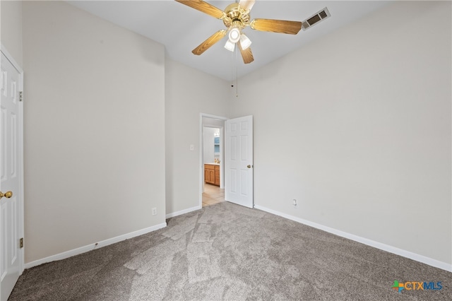 unfurnished bedroom featuring ceiling fan, light colored carpet, and a high ceiling