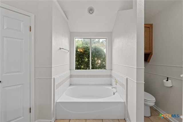 bathroom featuring tile patterned floors, a washtub, toilet, and lofted ceiling