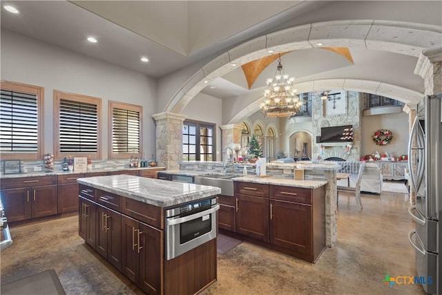 kitchen with a center island, stainless steel appliances, light stone counters, and sink