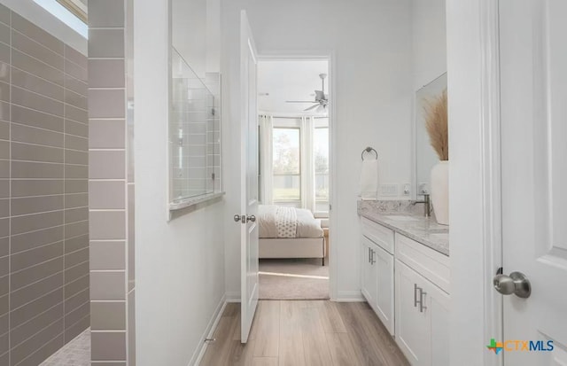 bathroom featuring walk in shower, ceiling fan, wood finished floors, and vanity