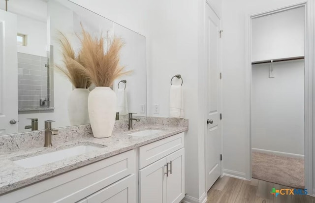 full bath with double vanity, wood finished floors, and a sink