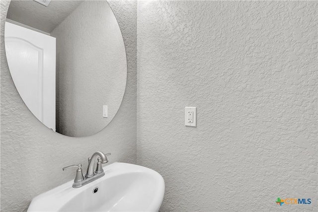 bathroom with a textured wall and a sink