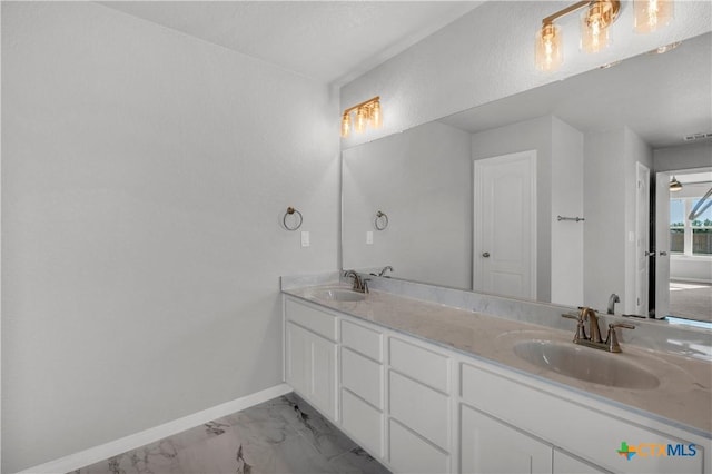 bathroom featuring baseboards, marble finish floor, a sink, and double vanity
