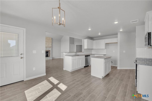kitchen featuring a fireplace, baseboards, open floor plan, and stainless steel appliances