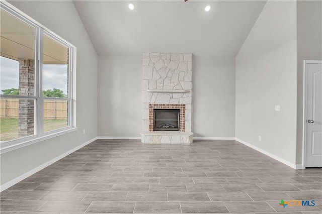 unfurnished living room with recessed lighting, baseboards, lofted ceiling, and a fireplace