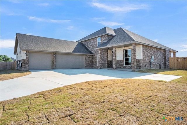 view of front of home featuring driveway, stone siding, fence, an attached garage, and a front yard