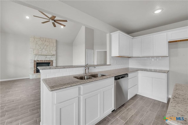 kitchen featuring wood tiled floor, lofted ceiling, light stone counters, dishwasher, and a sink