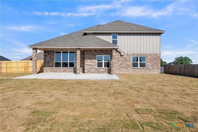 rear view of property featuring a lawn, a patio area, a fenced backyard, and brick siding