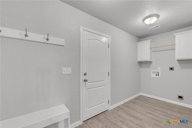 clothes washing area featuring hookup for a washing machine, hookup for an electric dryer, light wood-style floors, cabinet space, and visible vents