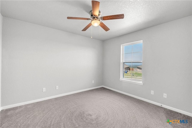 carpeted empty room featuring ceiling fan and baseboards