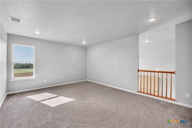 unfurnished room featuring baseboards, visible vents, carpet floors, and a textured ceiling