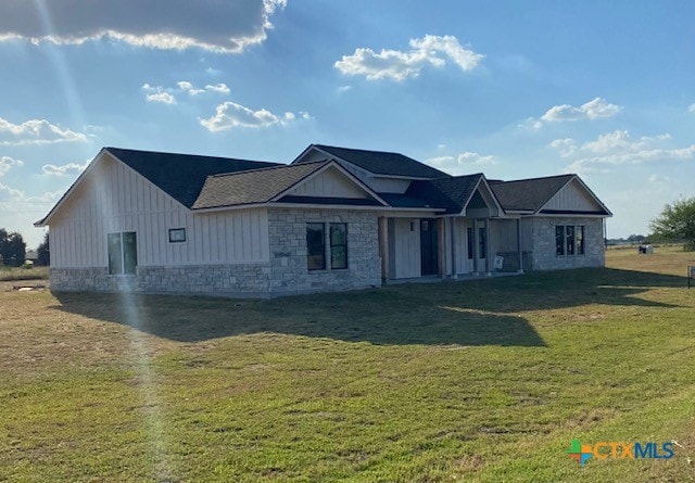 view of front of property with stone siding, board and batten siding, and a front yard