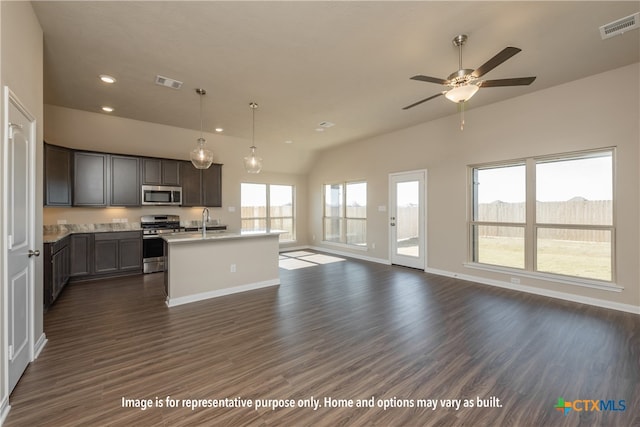 kitchen with stainless steel appliances, decorative light fixtures, dark hardwood / wood-style floors, sink, and a kitchen island with sink