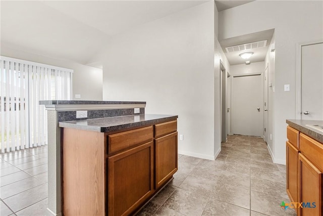 kitchen featuring vaulted ceiling, a kitchen island, and light tile patterned flooring