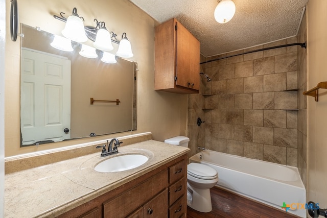 full bathroom with hardwood / wood-style flooring, tiled shower / bath, a textured ceiling, vanity, and toilet