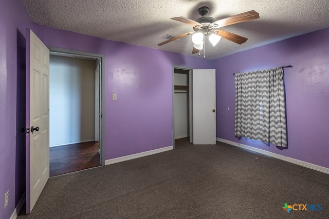 unfurnished bedroom with a closet, a textured ceiling, dark colored carpet, and ceiling fan