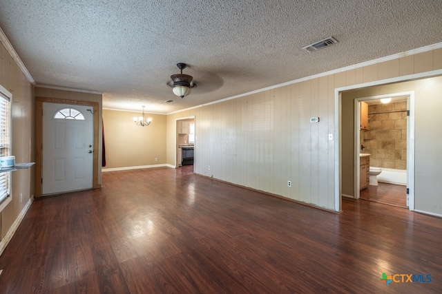 unfurnished living room featuring dark wood-type flooring, ceiling fan with notable chandelier, a textured ceiling, and ornamental molding