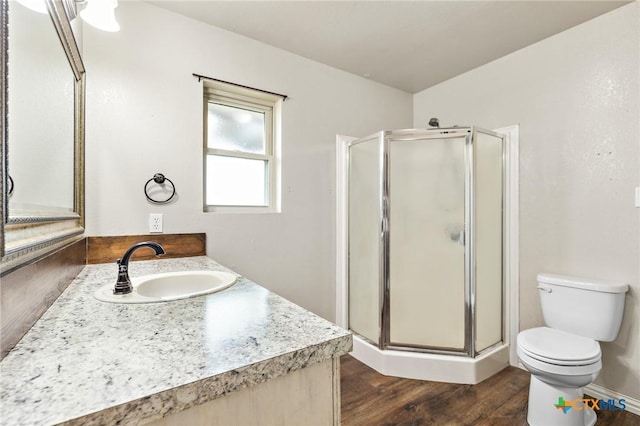 bathroom with vanity, a shower with shower door, toilet, and wood-type flooring