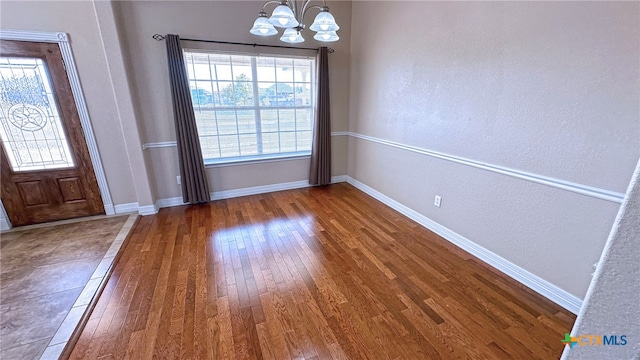 unfurnished dining area with a chandelier and dark hardwood / wood-style floors