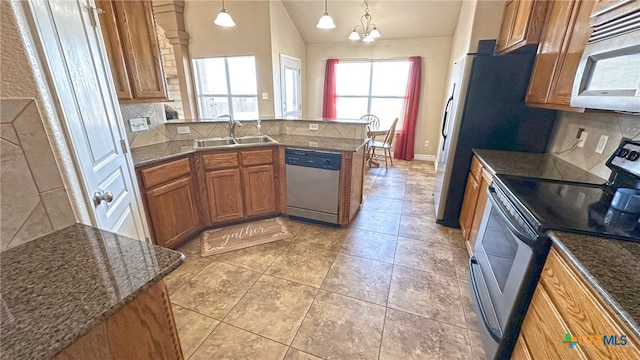 kitchen featuring tasteful backsplash, stainless steel appliances, pendant lighting, sink, and an inviting chandelier