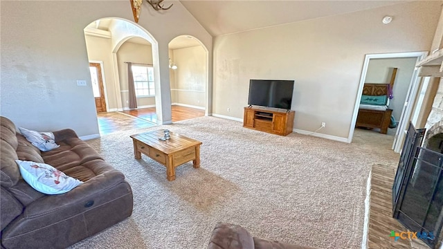 carpeted living room with a brick fireplace and lofted ceiling