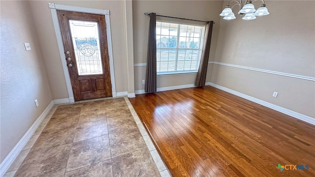 entrance foyer with a wealth of natural light, an inviting chandelier, and hardwood / wood-style flooring