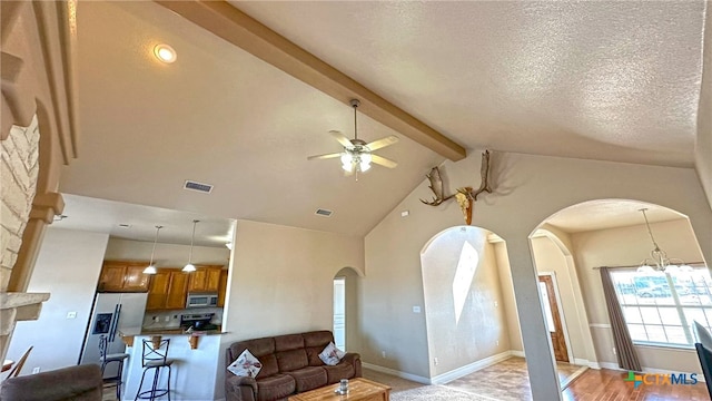 living room with beamed ceiling, ceiling fan with notable chandelier, a textured ceiling, high vaulted ceiling, and light hardwood / wood-style flooring