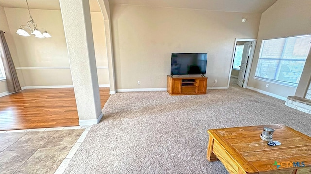 unfurnished living room with lofted ceiling, a chandelier, and hardwood / wood-style flooring