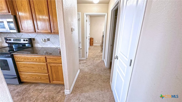 kitchen with appliances with stainless steel finishes, decorative backsplash, and light carpet