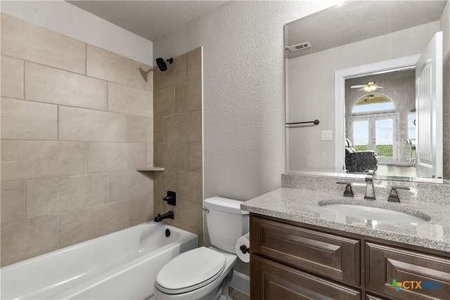 full bathroom with vanity, a textured ceiling, toilet, tiled shower / bath, and ceiling fan