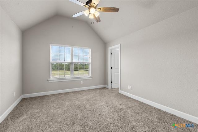 spare room featuring carpet floors, lofted ceiling, and ceiling fan