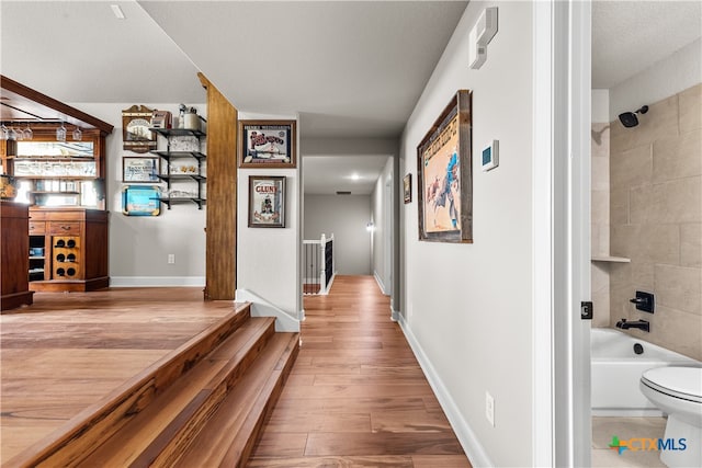 hallway featuring light hardwood / wood-style flooring and a textured ceiling