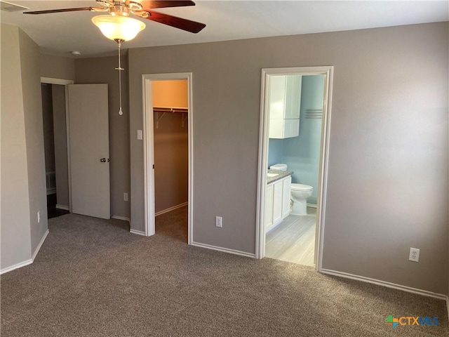 unfurnished bedroom with carpet, ensuite bathroom, ceiling fan, a spacious closet, and a closet