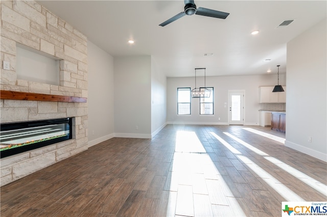 unfurnished living room featuring hardwood / wood-style floors, a fireplace, and ceiling fan with notable chandelier