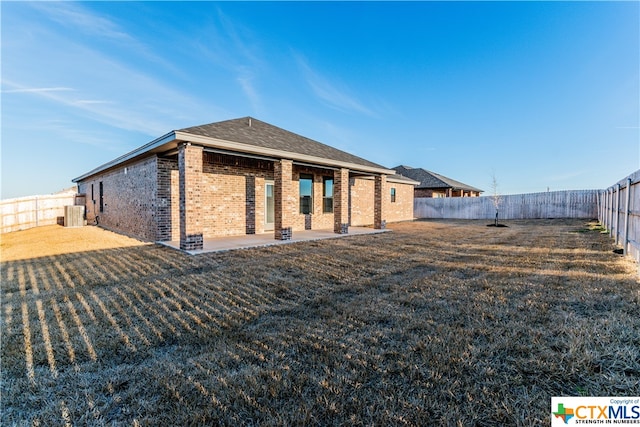 rear view of property with central AC unit, a patio, and a yard