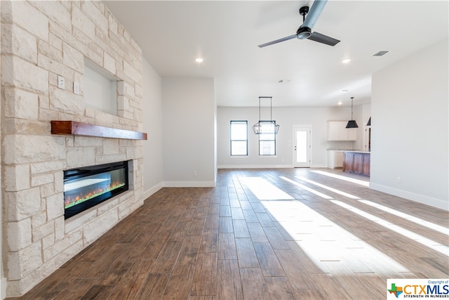 unfurnished living room featuring hardwood / wood-style floors, ceiling fan, and a fireplace