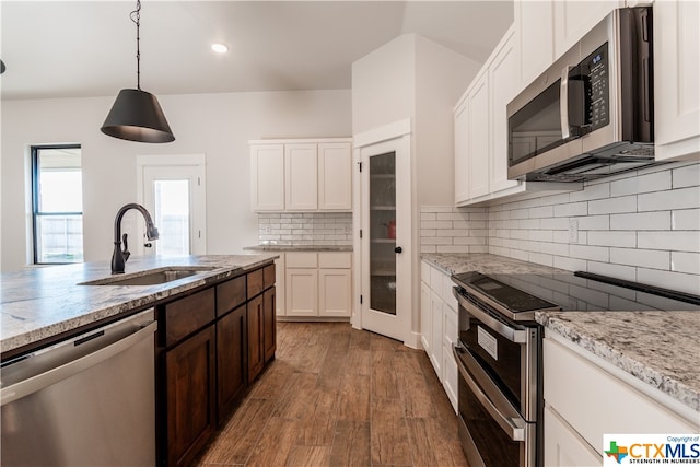 kitchen featuring stainless steel appliances, decorative light fixtures, decorative backsplash, hardwood / wood-style floors, and white cabinets