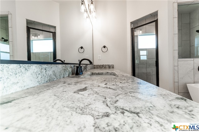 bathroom with walk in shower, vanity, and a wealth of natural light