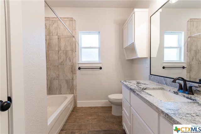 full bathroom featuring a wealth of natural light, vanity, tiled shower / bath combo, and toilet