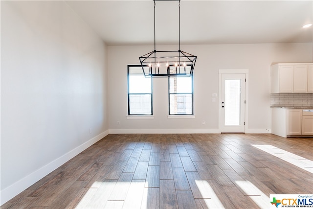 unfurnished dining area featuring a notable chandelier and light hardwood / wood-style flooring